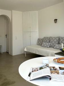 a living room with a couch and a table with a newspaper at Blue and white Mykonos in Mikonos +11 photos