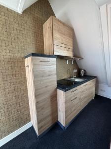 a kitchen with a sink and a wooden cabinet at Hotel West Inn Aan Zee in Den Oever +16 photos