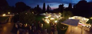 un grupo de personas de pie en un jardín con sombrillas en Bed and Breakfast La Corte degli Ulivi, en Civitavecchia