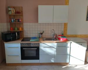 a kitchen with white cabinets and a stove and a sink at Ferienwohnung Athena in Pirna