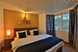 Un dormitorio con una cama grande y una ventana en Lemas Holiday Bungalow, en Nuwara Eliya