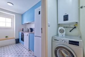 a washing machine in a kitchen with blue cabinets at New flat and central in Lisbon