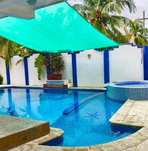 a large swimming pool with a green umbrella at Casa Coral in San José de Guatemala