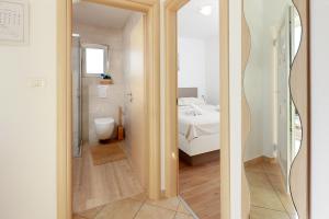 a room with a bed and a bathroom with a mirror at Apartments Omanović in Čižići +64 photos
