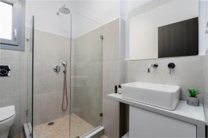 a white bathroom with a sink and a shower at Terracotta Sunset Naxos in Galanádhon