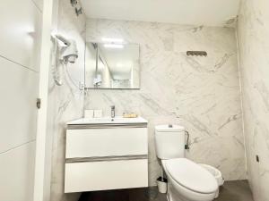 biała łazienka z toaletą i lustrem w obiekcie Aluche Aparment B w Madrycie