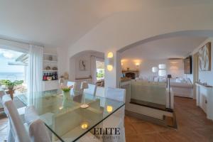 una sala da pranzo e un soggiorno con un tavolo di vetro di Prestigiosa Villa di Lusso con Vista Mozzafiato a Porto Cervo