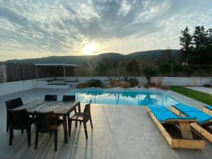 オルネゾンにあるLe point BE - Magnifique villa avec piscine chauffée - de mai à septembre - pour 6 personnesのテーブルと椅子とプールのあるパティオ