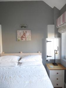 a bedroom with a white bed and a night stand at Oxley Cottage in Alford