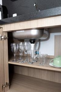 una fila de copas de vino sentadas en un estante en Guaja 745 - Apartamento Bento, en Belo Horizonte