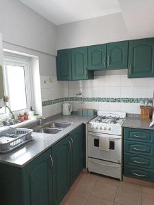 cocina con armarios verdes, fogones y fregadero en Departamento Momó, en San Miguel de Tucumán
