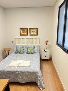 a bedroom with a bed and a table and a window at Guaja 745 - Apartamento Luna in Belo Horizonte