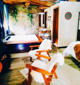 a room with two beds and two chairs in it at Chalé Bosque das Pedras in Núcleo Mauá