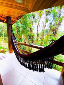 a hammock on a porch with trees in the background at Chalé Bosque das Pedras in Núcleo Mauá