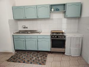 a kitchen with blue cabinets and a sink and a stove at Villa Madame in Monacizzo