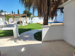 a patio with a palm tree and a swing at Villa Madame in Monacizzo