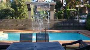 een fontein met twee stoelen en een tafel voor een zwembad bij Villa Astravi in Ialyssos