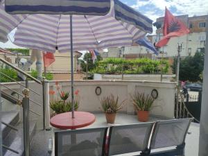 a patio with a table and two umbrellas on a balcony at Ami guest house in Fier