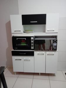 Il comprend une cuisine blanche équipée d'un four micro-ondes et d'une cuisinière. dans l'établissement Apartamento com área de lazer completa!, à Valparaíso de Goiás