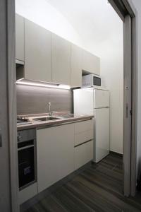 Una cocina blanca con fregadero y refrigerador. en Sunrise, en Castellana Grotte