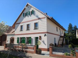 a house with green shuttered windows and a staircase at Elsternest - Ferienwohnungen mit Sauna & Ostereierwerkstatt in Elsterheide