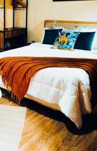a bedroom with a large bed with orange blanket and blue pillows at Chalé Bosque das Pedras in Núcleo Mauá