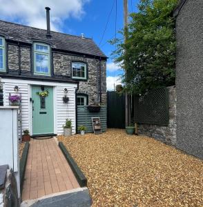 a house with a gravel driveway in front of it at Harlequin Cottage in Llangernyw