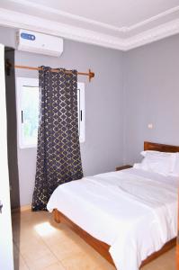 a bedroom with a white bed and a window at ACNELA Residence Kribi Cameroon in Kribi