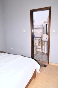 a bedroom with a bed and a bathroom with a sink at ACNELA Residence Kribi Cameroon in Kribi