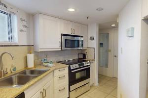 a kitchen with a sink and a microwave at 105 - Caprice Resort in St. Pete Beach
