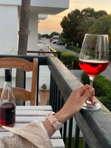 a person holding a glass of red wine on a balcony at Adosado Dúplex Bahía de la Plata - Vistas Increíbles al Mar, Terraza y Jardín Privado in Zahara de los Atunes