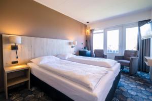 a hotel room with a large bed and a chair at Hotel Hofker in Nes