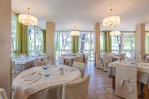Un restaurante con mesas y sillas blancas y candelabros. en Hotel Deborah, en Milano Marittima