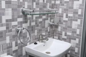 a white sink in a bathroom with a tile wall at Reliable Cosy Apartment 1 in Trofwi