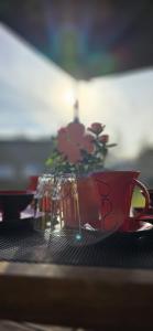 ein Tisch mit einer roten Tasse und einer Vase mit Blumen in der Unterkunft Ferienhaus Wiese und Meer in Zinnowitz