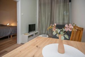 a vase with flowers sitting on a wooden table at Velora apartments in Subotica