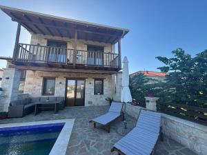 a house with a pool and two chairs and an umbrella at Luxury stone villas in Afitos St'aloni in Kassandria
