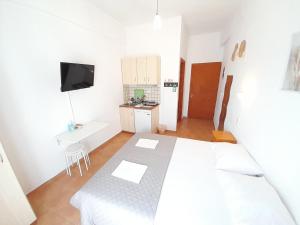 a white bedroom with a bed and a small kitchen at Lydia Mare in Agios Kirykos