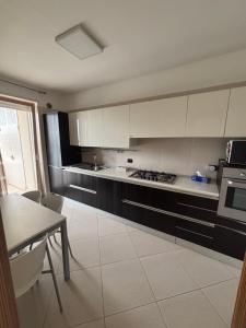 cocina con armarios blancos, mesa y fogones en Casa Mara, en Macchie 9 fotos más