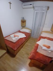 2 Betten in einem Zimmer mit einem Kreuz an der Wand in der Unterkunft N i N in Međugorje