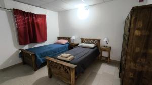 - une chambre avec 2 lits et un rideau rouge dans l'établissement Casa con cochera y patio cerrado, Ruka del Rio, à Choele Choel