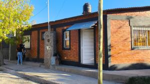 une femme debout à l'extérieur d'un bâtiment en briques dans l'établissement Casa con cochera y patio cerrado, Ruka del Rio, à Choele Choel