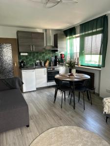 a kitchen and living room with a table and chairs at Gemütliches 2-Zimmer-Apartment im Fichtelgebirge - nahe der Skipiste mit Terrasse & Free Parking in Mehlmeisel