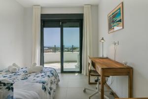 Un dormitorio con una cama y un escritorio y una ventana. en Split-level apartment with spa & private rooftop, en Málaga