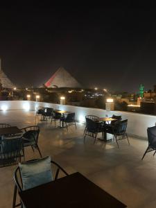 カイロにあるArabian Nights Pyramids Guesthouseの- ピラミッドのあるパティオ(夜間のテーブルと椅子付)