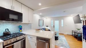 Una cocina con gabinetes blancos y un horno de estufa. en Modern Renovated 1br W Pvt Entrance Prime Loc, en Cambridge