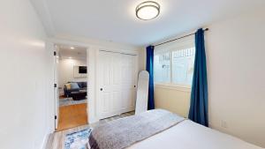 1 dormitorio con 1 cama con cortinas azules y ventana en Modern Renovated 1br W Pvt Entrance Prime Loc, en Cambridge