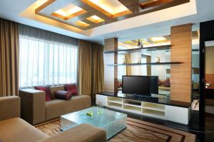 a living room with a couch and a television at Novotel Balikpapan in Balikpapan