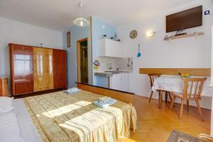 Cette chambre comprend un lit, une table et une cuisine. dans l'établissement Apartment Agava, à Miholašćica