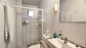 a white bathroom with a sink and a shower at Apartamento Vista Parque in Cascavel